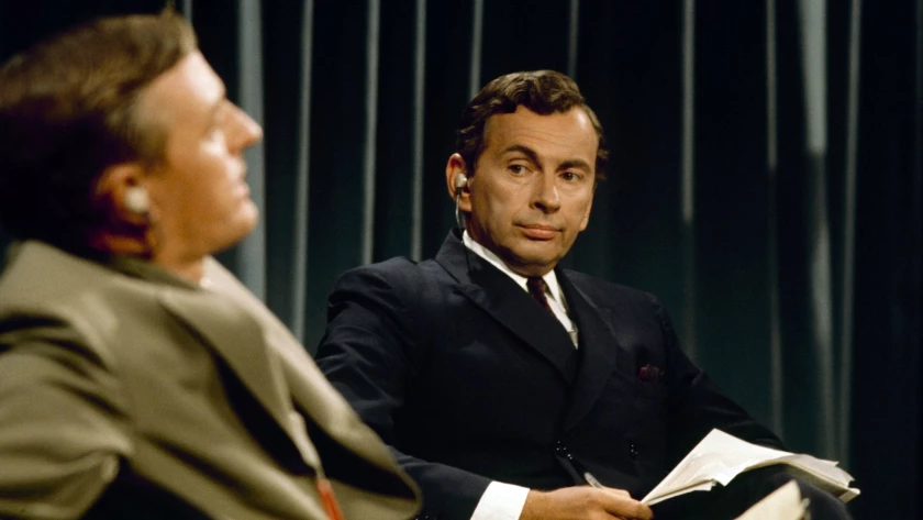 Una persona sentado con un traje de color negro

Descripción generada automáticamente con confianza media