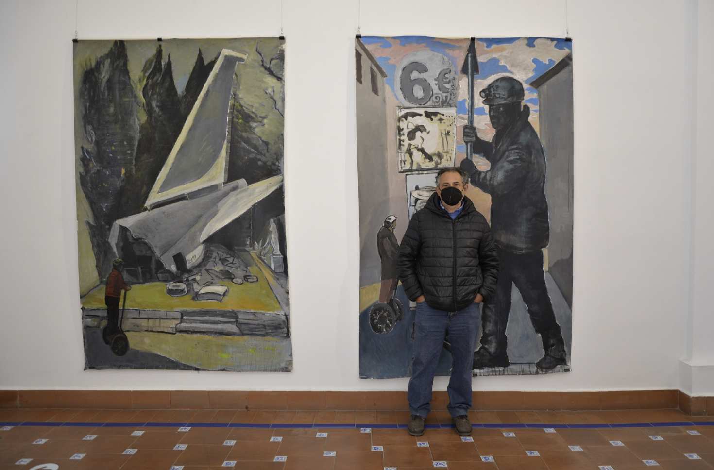 Rafael Alvarado junto a dos de sus obras en la exposición La ciudad laberinto.